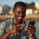 pescador da cidade de Raposa, no Maranhão, segurando celular e sorrindo, acertando acessar o aplicativo, apontando para o celular..jpg
